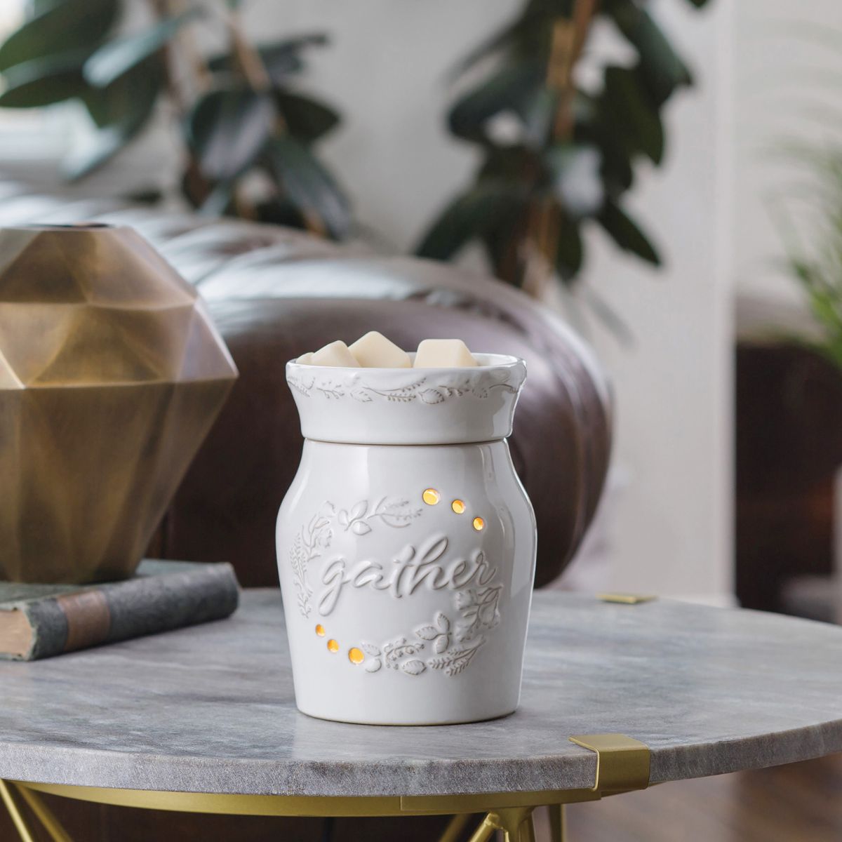 White ceramic wax warmer with 'Gather' text on a marble surface with decorative elements.