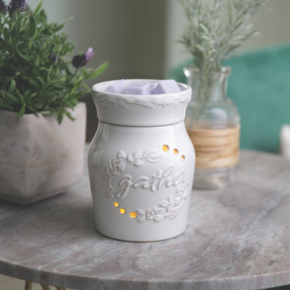 White ceramic wax warmer with 'gather' text on a marble surface with plants in the background
