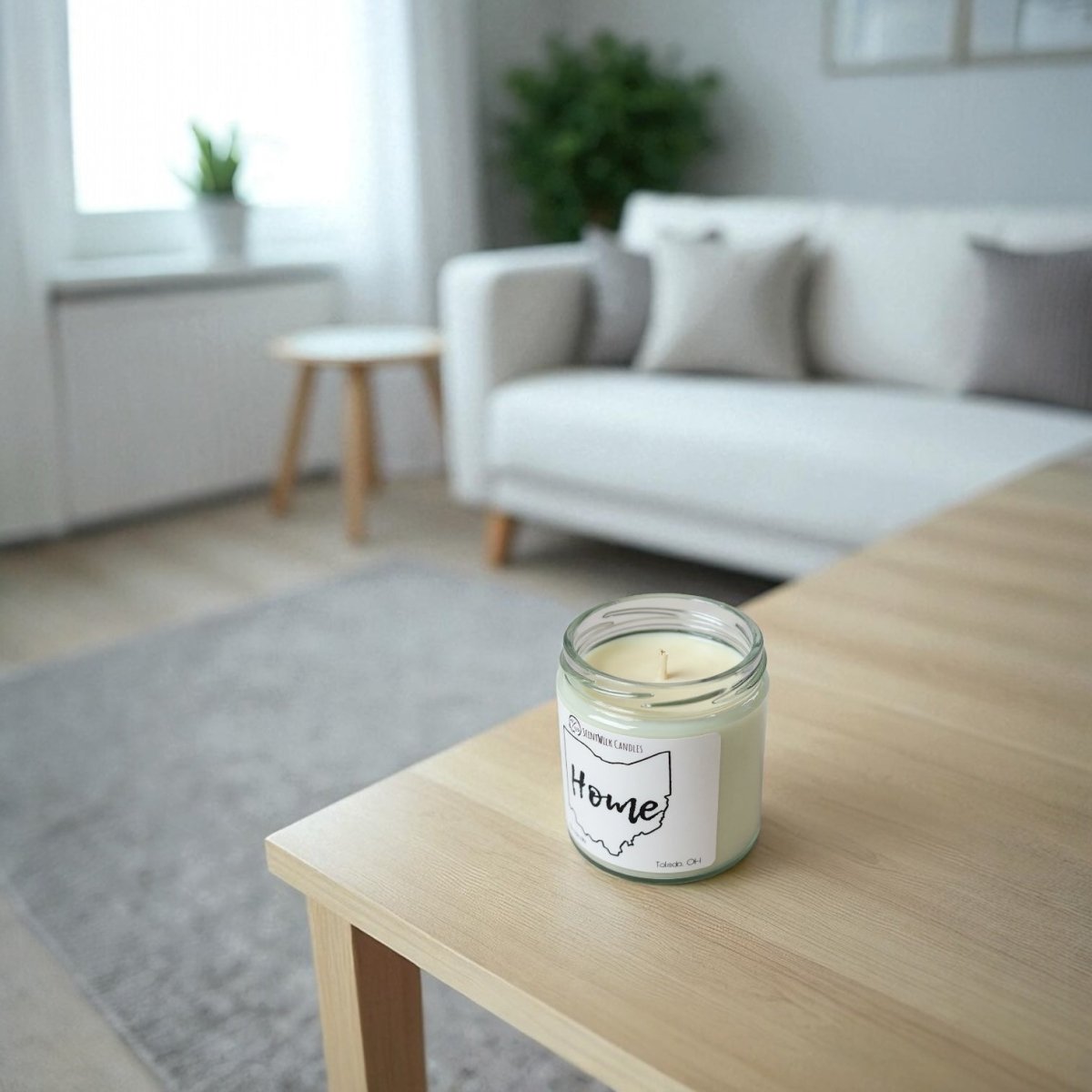 Candle with 'Home' label on a wooden table in a living room setting