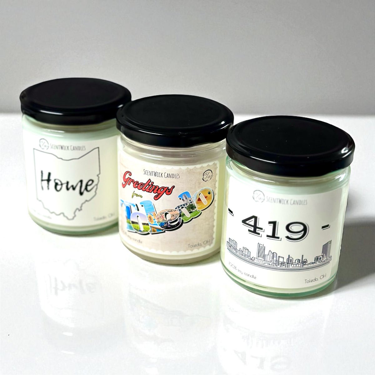 Three candles with Ohio labels on a white surface