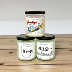 Three Toledo soy candles with black lids on a wooden surface