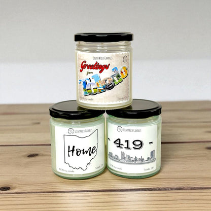 Three Toledo soy candles with black lids on a wooden surface