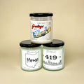 Three Toledo, Ohio, candles with black lids on a beige background