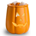 Orange pumpkin-shaped wax warmer with a jack-o'-lantern face on a white background