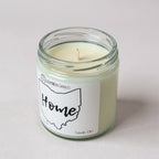 Candle in a glass jar with a 'Home' label on a light background