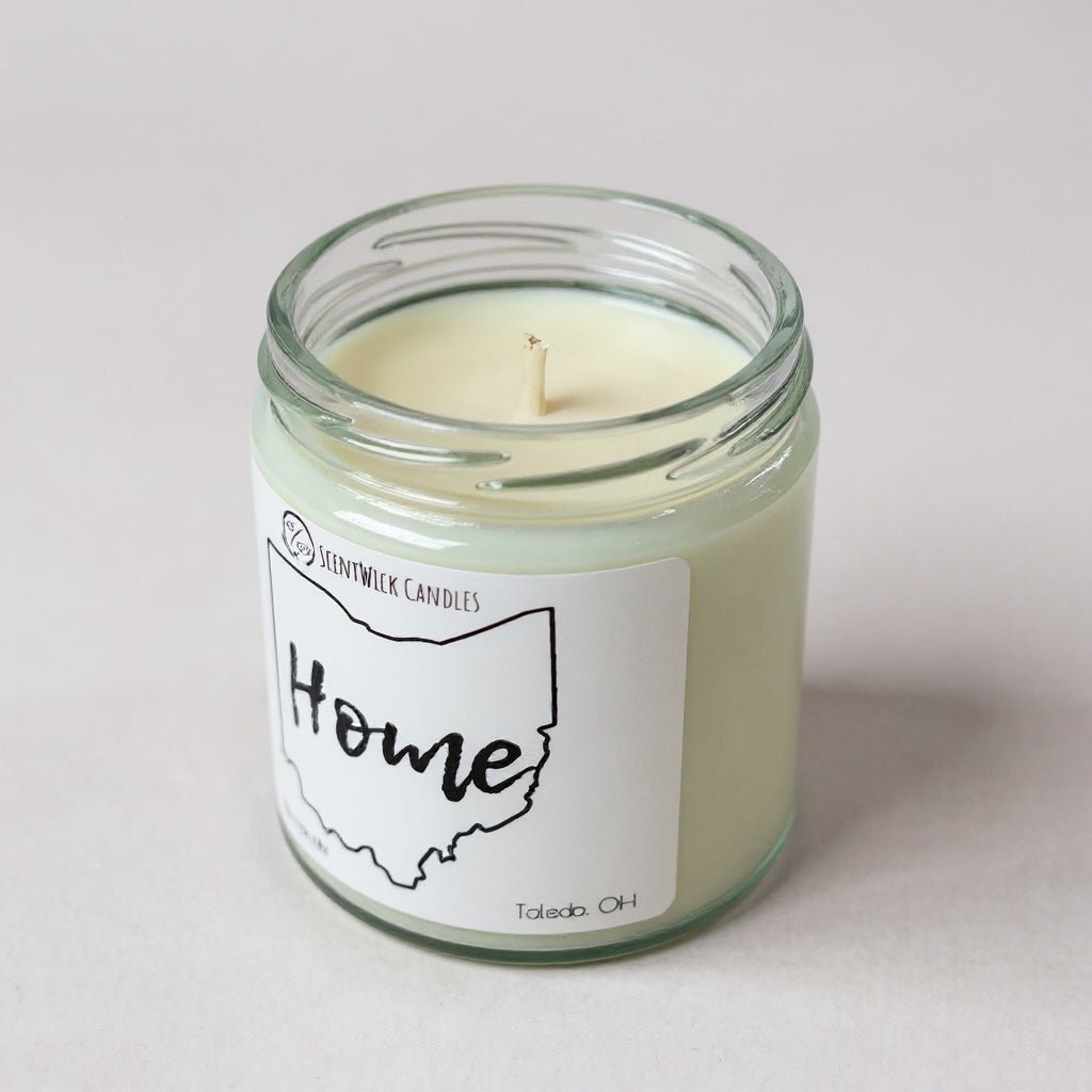 Candle in a glass jar with a 'Home' label on a light background