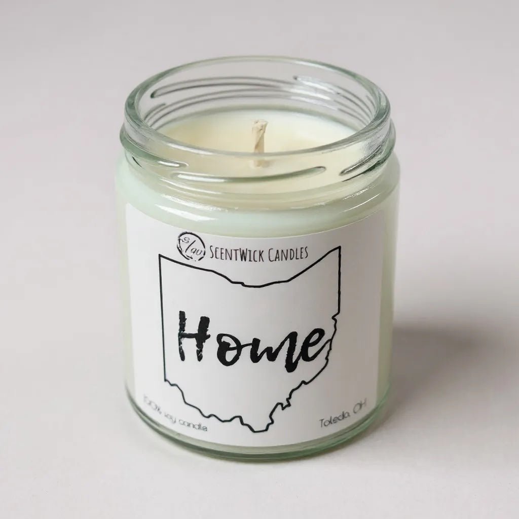 Candle in a glass jar with a 'Home' label on a white background