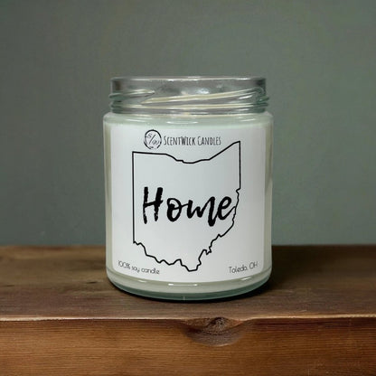 Candle in a glass jar with a 'Home' label on a wooden surface and gray background