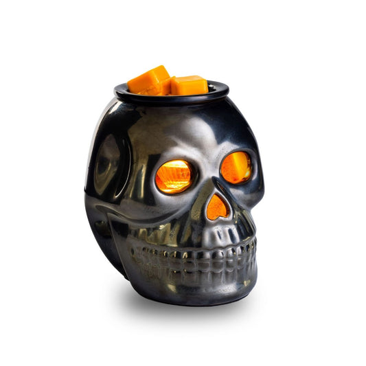 Skull-shaped wax warmer with glowing eyes on a white background
