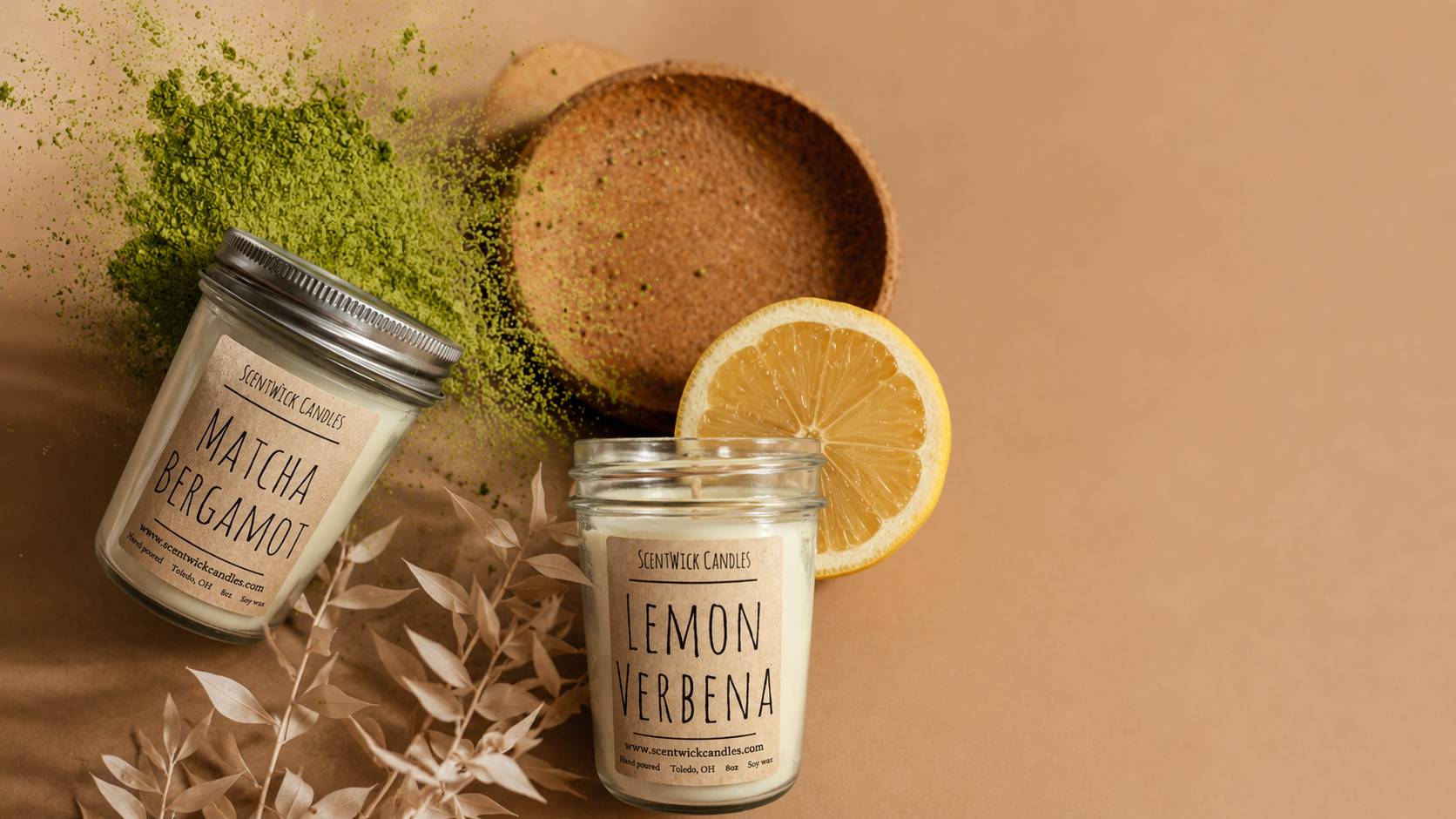 Two candles labeled 'Matcha Bergamot' and 'Lemon Verbena' on a brown background with greenery and a lemon.
